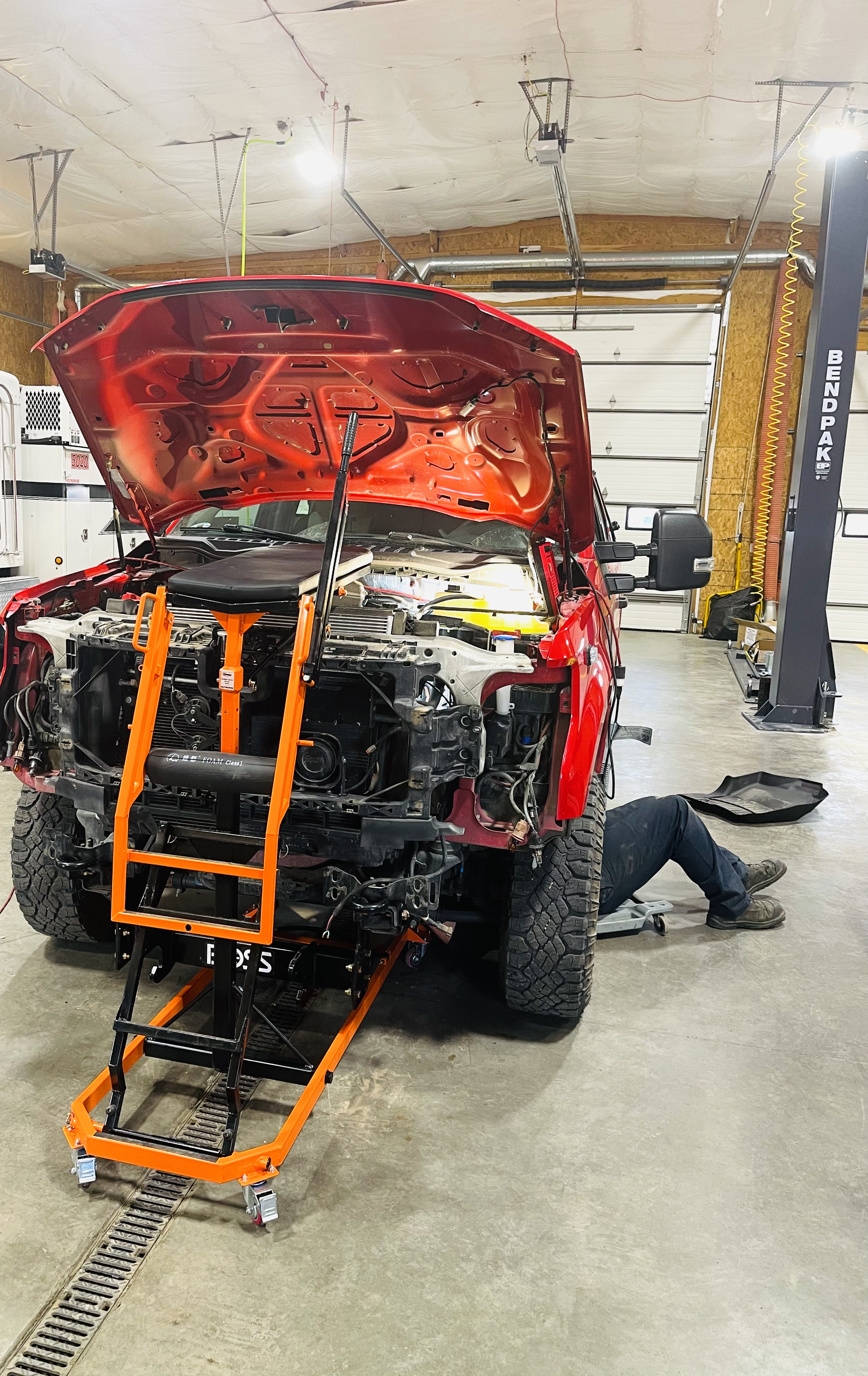 Pickup truck with hood up and mechanic underneath