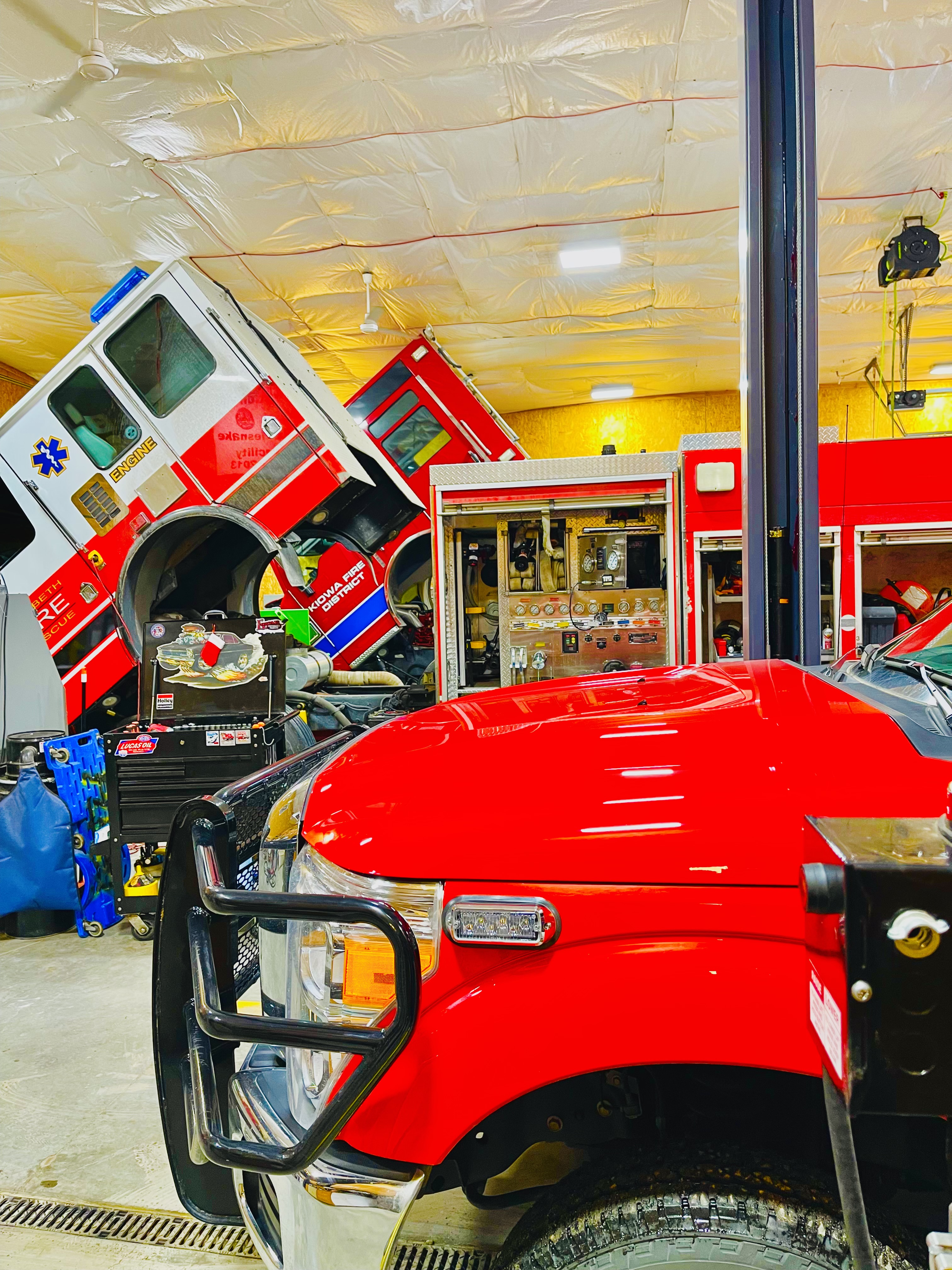 two fire trucks with their cab's tilted inside the fleet shop