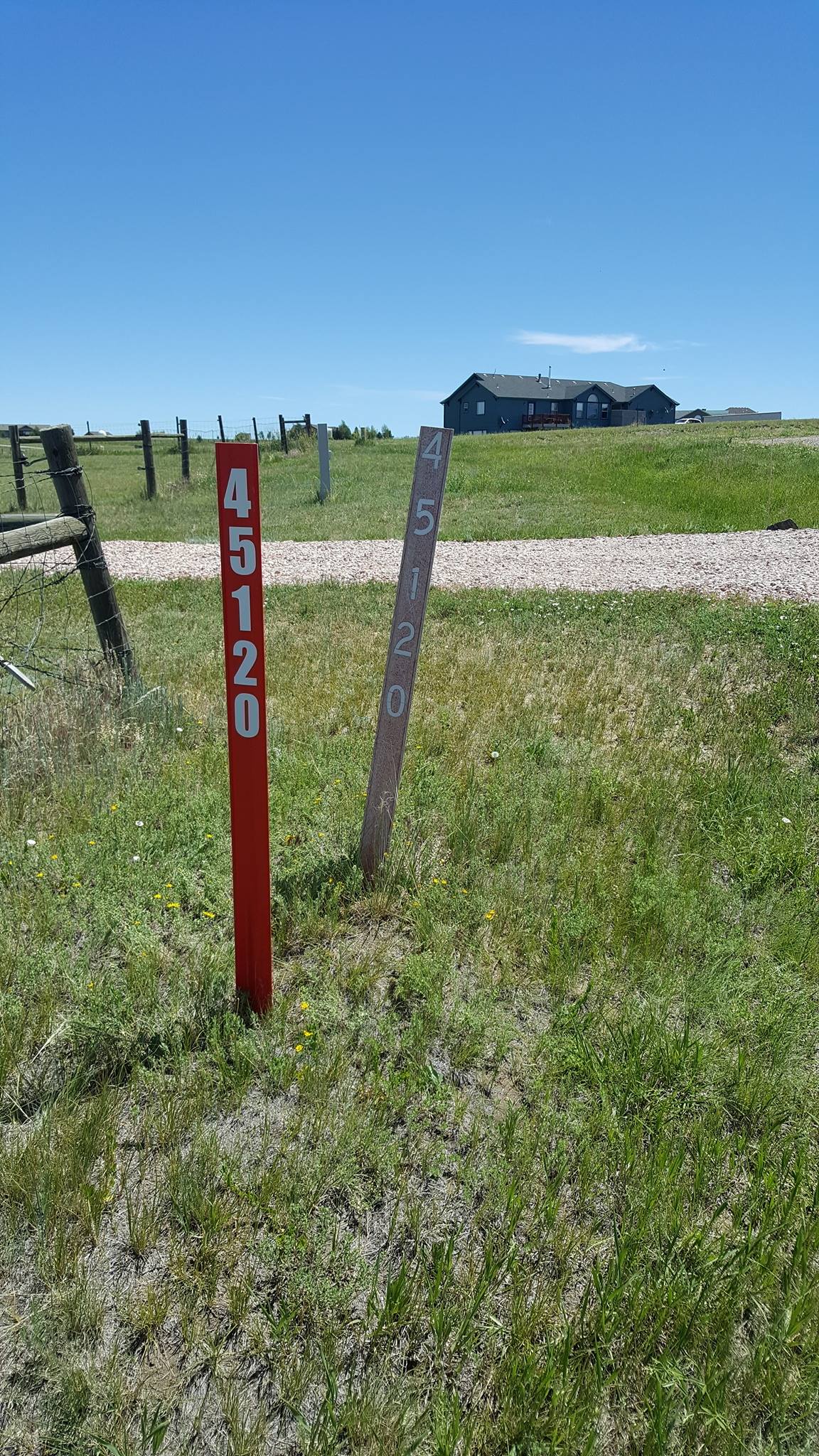Photo of new fiberglass address marker with 4 inch reflective numbers installed next to an old marker with faded non reflective numbers