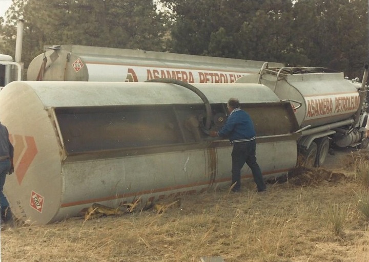 Oil tanker rolled on its side with a suction hose removing it's contents