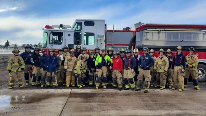 Group photo of firefighters standing in front of a fire engine